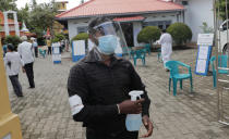 A Sri Lankan polling officer wearing mask and face shield stands holding a sanitizer sprayer at the entrance to a polling center during the parliamentary election in Colombo, Sri Lanka, Wednesday, Aug. 5, 2020. The election was originally scheduled for April but was twice postponed due to the COVID-19 pandemic. (AP Photo/Eranga Jayawardena)