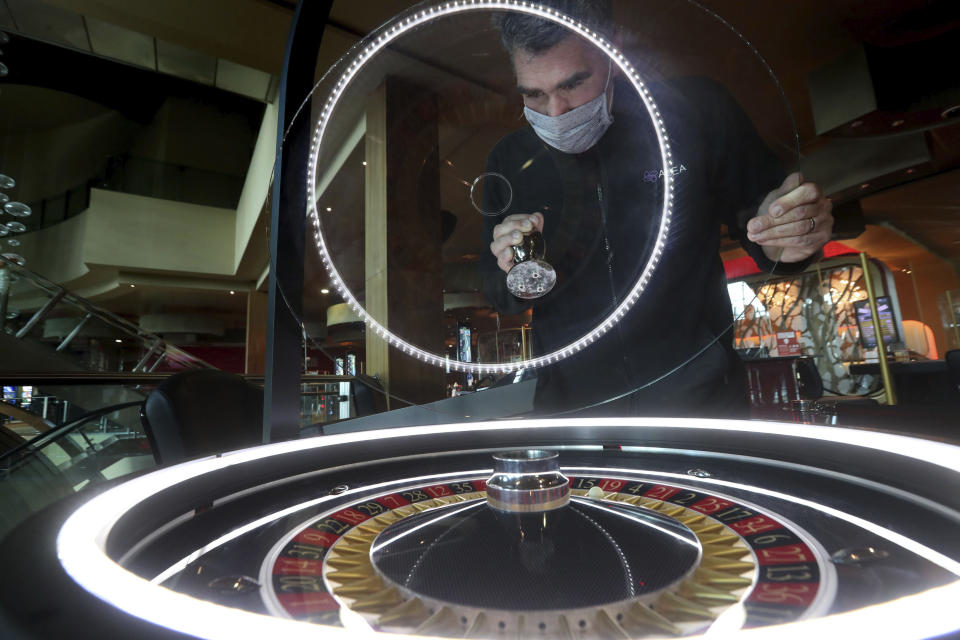 Stuart Mochrie checks the electronic roulette table ahead of opening today at the Alea Casino in Glasgow, Scotland, Monday, Aug. 24, 2020. Scotland continues with the gradual lifting of restrictions for bowling alleys, bingo halls and casinos, to ease out of lockdown. (Andrew Milligan/PA via AP)