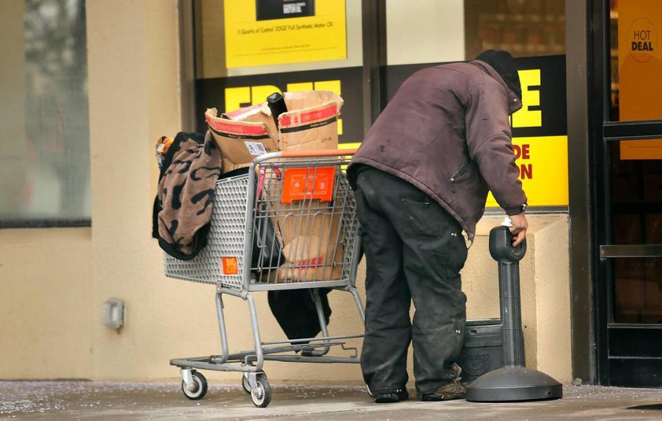 An man searches for cigarettes outside the doors of an auto parts store at the Highlands Center shopping area off Highway 395 in Kennewick.