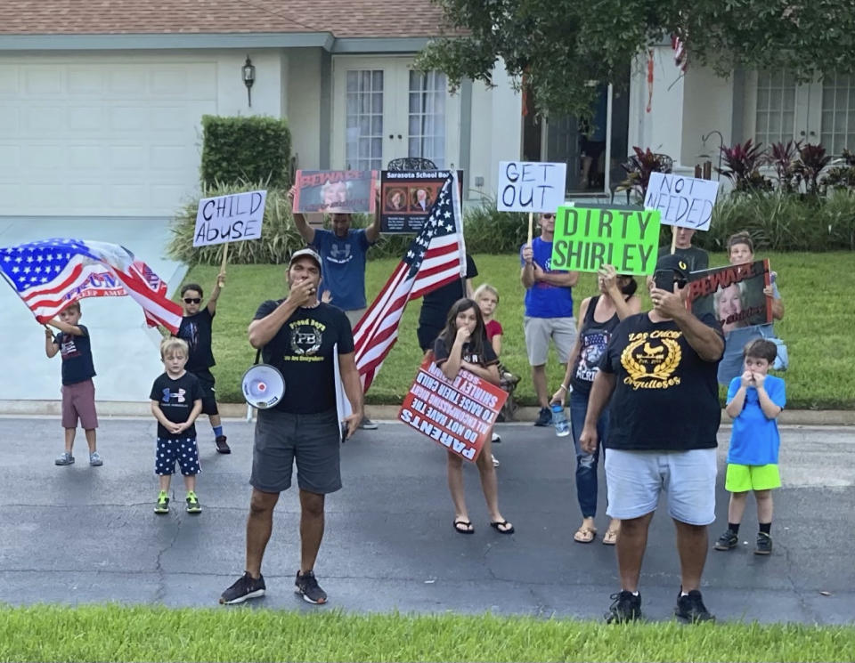 In this photo provided by former Sarasota County School Board Chair Shirley Brown, Proud Boy member James Hoel and others gather outside her home for an anti-mask protest on Oct. 4, 2021. "We see you in there, Shirley. We want you to come out for a redress of grievances," Hoel said through a megaphone. (Shirley Brown via AP)