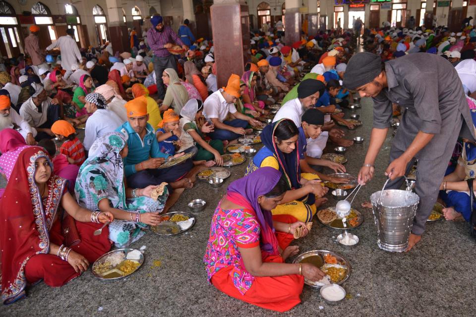 Sikh devotees eat a communal vegetarian meal, known as langar, in a hall at the Golden temple in Amritsar in 2015. (Photo: NARINDER NANU via Getty Images)