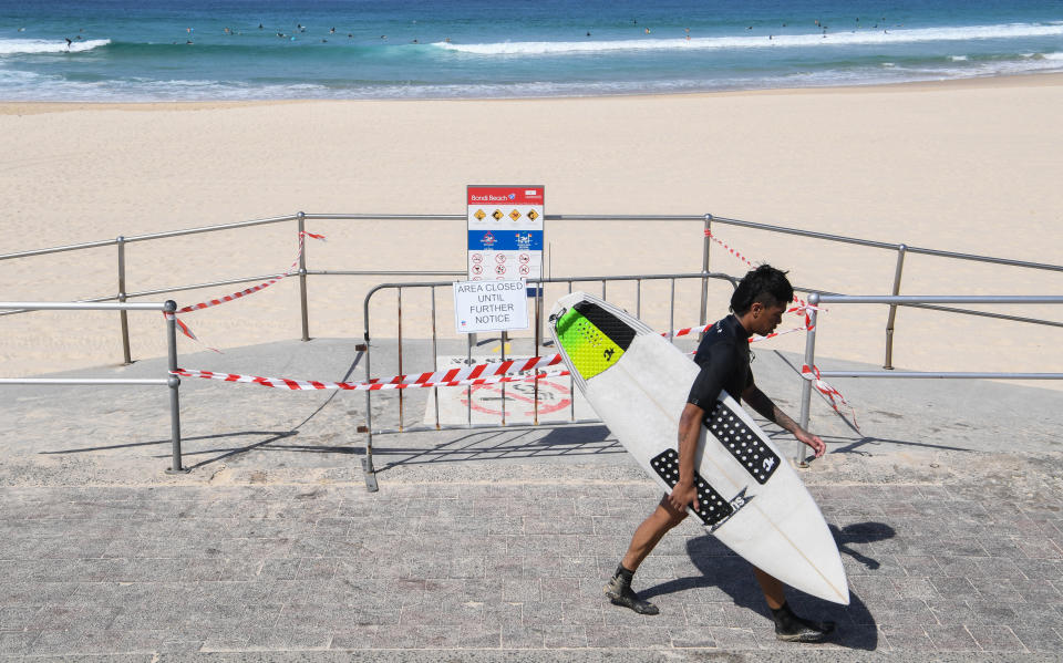 SYDNEY, AUSTRALIA - MARCH 22: Lone surfers at an empty Bondi beach after authorities banned people from gathering on it on March 22, 2020 in Sydney, Australia. Prime Minister Scott Morrison on Friday introduced further measures to help stop the spread of COVID-19, implementing new rules limiting the number of people inside a venue to one every 4 square metres. Non-essential gatherings of 100 or more people indoors are banned, along with outdoor gatherings of more than 500 people in a bid to contain the spread of COVID-19. A travel ban on all visitors who are not Australian citizens or residents or their direct relations arriving into the country is now in place. There are now 1286 confirmed cases of COVID-19 In Australia and the death toll now stands at seven. (Photo by James D. Morgan/Getty Images)