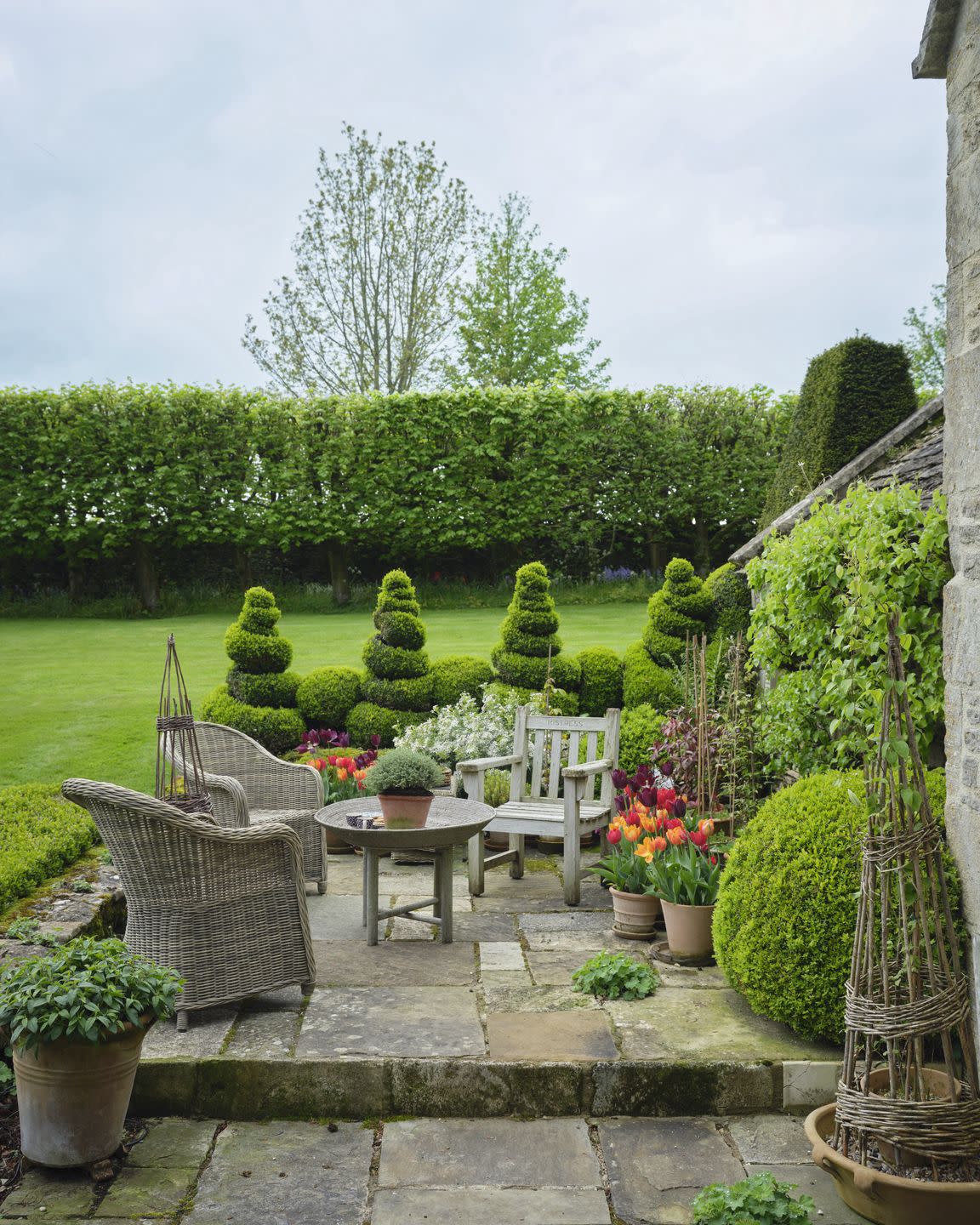 cotswolds home of oka cofounder sue jones charming spiral topiaries edge the sunny front terrace woven chairs