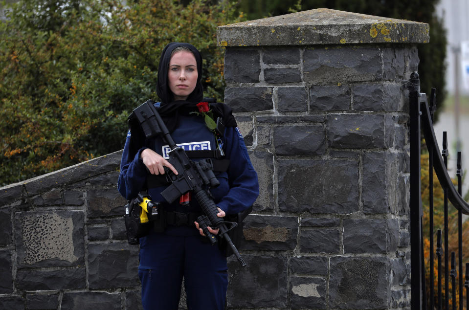 FILE - A police officer stands guard with a rose at the service for a victim of the March 15 mosque shootings at the Memorial Park Cemetery in Christchurch, New Zealand, on March 21, 2019. New Zealand’s government will overhaul the tighter gun laws introduced after a deadly mass shooting by a white supremacist five years ago, because they put excessive burdens on gun owners who feel vilified by law enforcement and the public, the lawmaker leading the changes said. (AP Photo/Vincent Yu, File);;;