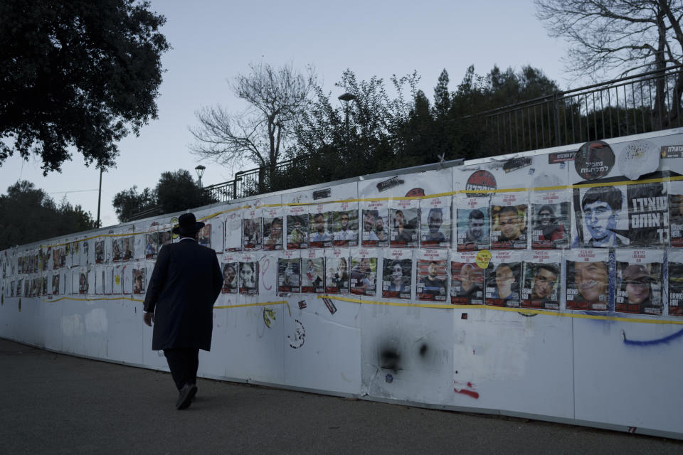 A man looks at photographs on a wall of hostages who were abducted during the Oct. 7, unprecedented Hamas attack on Israel, in Jerusalem, Israel, Tuesday, Jan. 30, 2024. (AP Photo/Leo Correa)