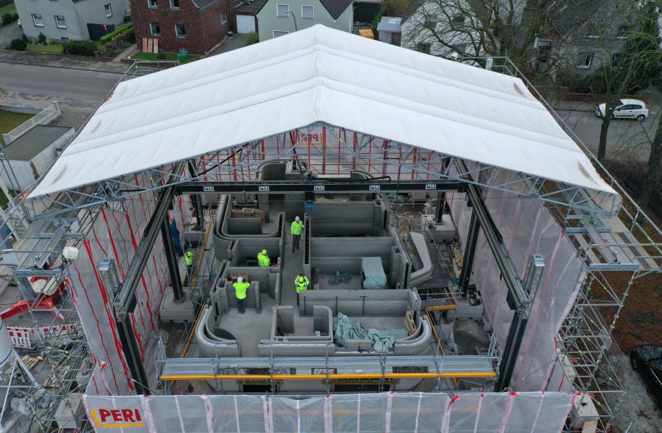 Construction workers standing in the scaffolded construction site of a house