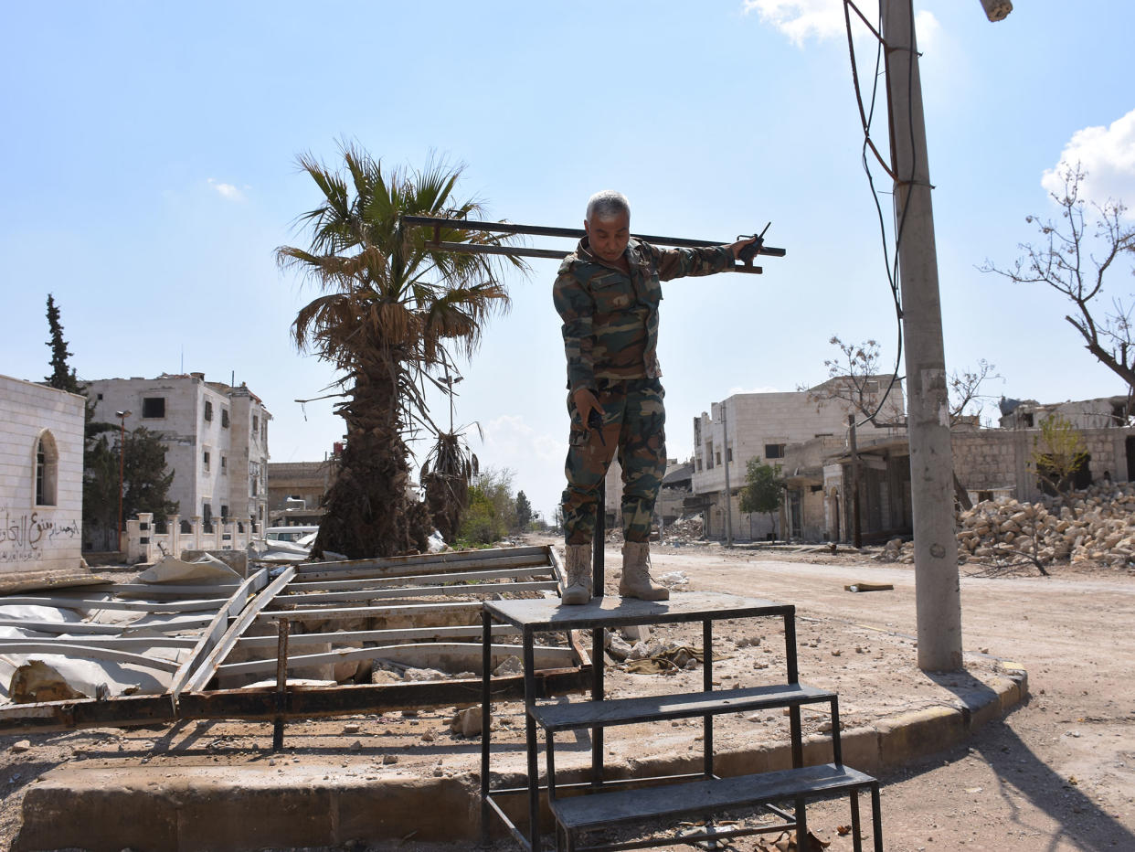 A Syrian soldier demonstrates how the crucifixion stand erected and used by Isis works: photography by George Ourfalian