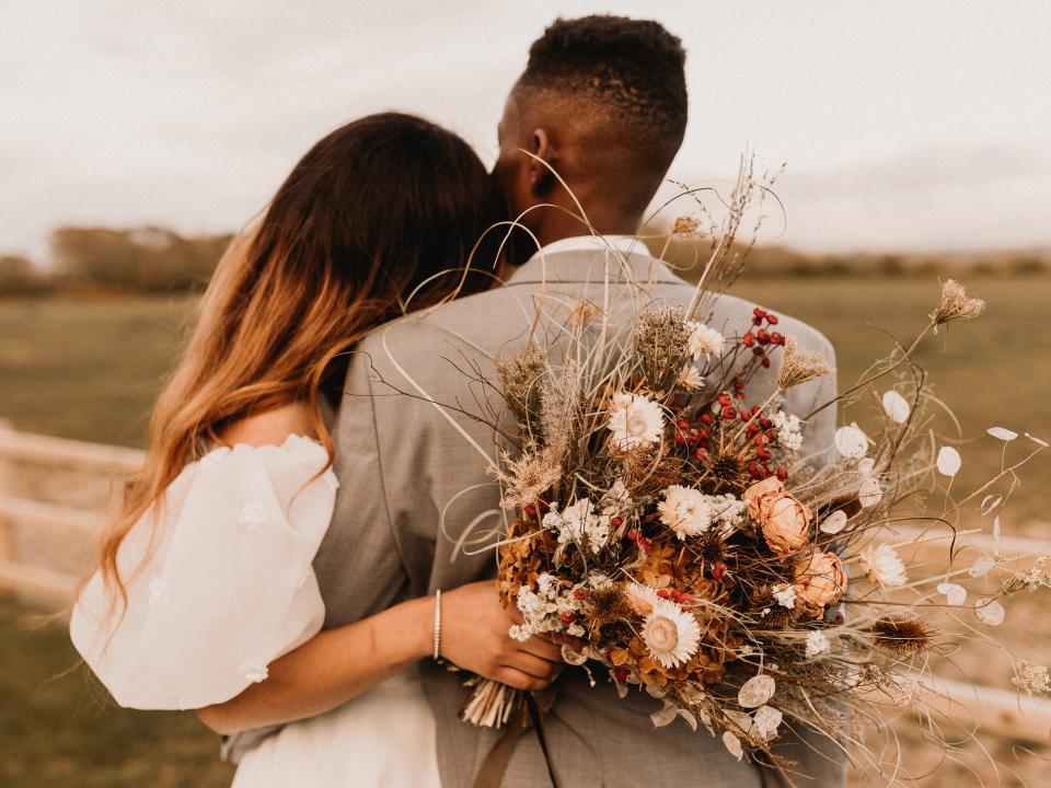 The bride and groom face away from the camera and look into a field