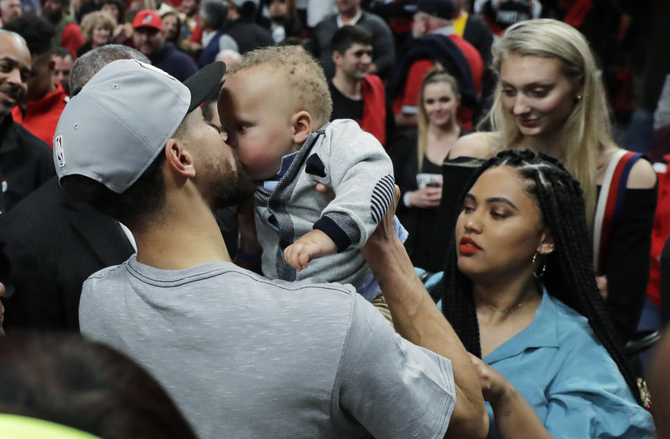 Golden State Warriors guard Stephen Curry, left, kisses his son Canon, as his wife Ayesha, lower right, looks on, at the end of Game 4 of the NBA basketball playoffs Western Conference finals against the Portland Trail Blazers, Monday, May 20, 2019, in Portland, Ore. The Warriors won 119-117 in overtime. (AP Photo/Ted S. Warren)