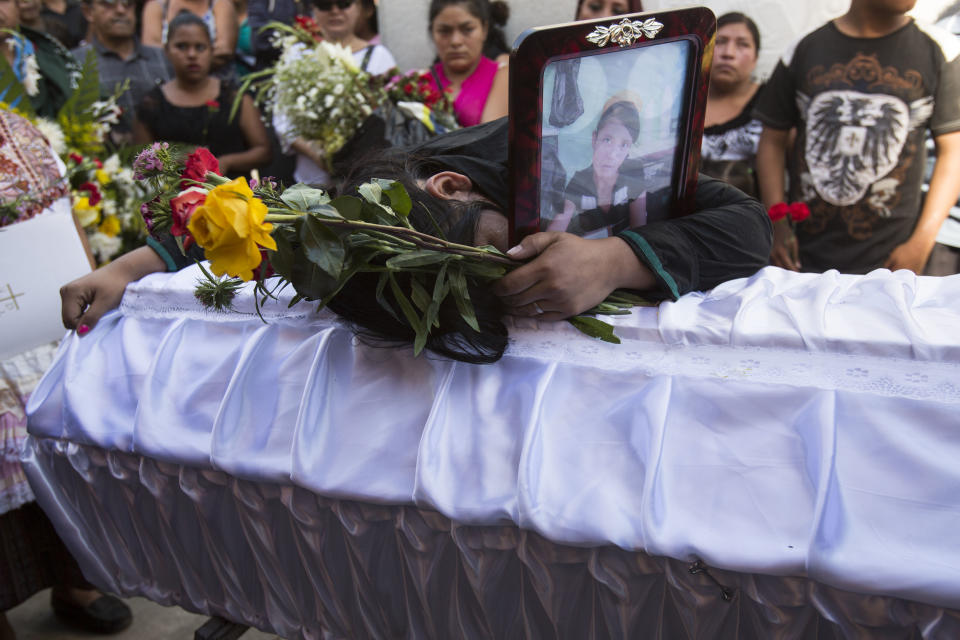 FILE - In this March 17, 2017 file photo, Shirley Palencia mourns over the coffin containing the remains of her 17-year-old sister Kimberly Palencia Ortiz, who died in the Virgen de la Asuncion Safe Home fire, at the cemetery in Guatemala City. Palencia Ortiz had been a ward of the state for nearly a year. Her father was in prison, her mother had disappeared, and her grandmother did not have the means to take care of her. (AP Photo/Moises Castillo, File)