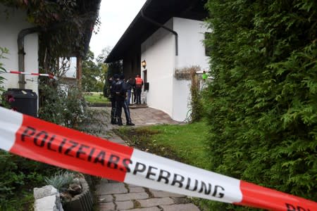 Police officers and rescue workers stand in front of a house where, according to police, five people were found dead in Kitzbuehel