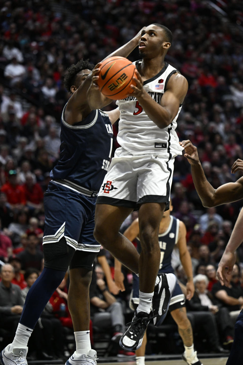 San Diego State guard Lamont Butler (5) goes up to shoot past Utah State forward Great Osobor (1) during the first half of an NCAA college basketball game Saturday, Feb. 3, 2024, in San Diego. (AP Photo/Denis Poroy)