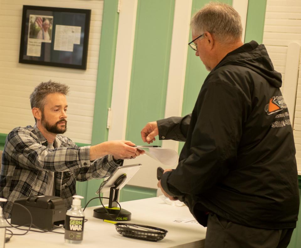 Polling volunteer Josh Clark hands a ballot to Paul Horbaly during Tuesday's primary election at the Freedom Town Hall.