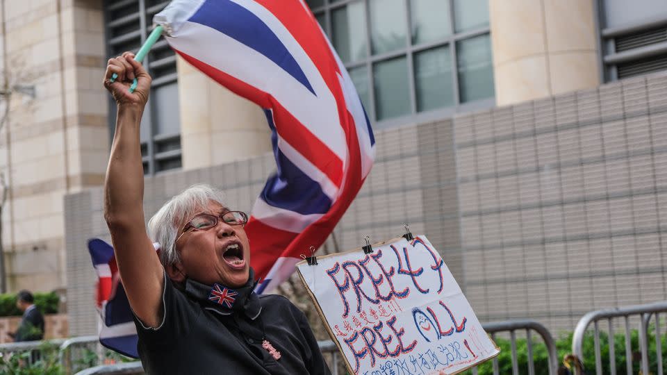Alexandra Wong, 67, waves a British flag and calls for the release of the 47 pro-democracy defendants outside the West Kowloon Court in Hong Kong on November 29, 2023. - Noemi Cassanelli/CNN