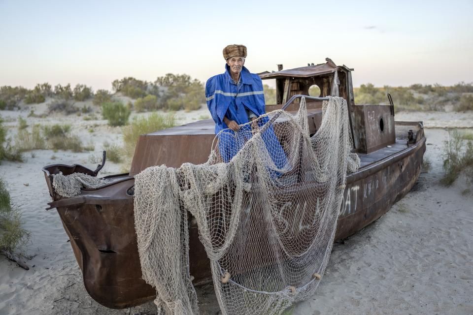 Gunesh Bai poses for a photo in front of an old boat in the area where the Aral Sea once was in Muynak, Uzbekistan, Wednesday, July 12, 2023. (AP Photo/Ebrahim Noroozi)