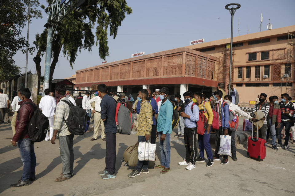 Indian passengers wait for transportation after arrival at a railway station, during a curfew imposed in Ahmedabad, India, Friday, Nov. 20, 2020. In a drastic move to stem the COVID-19 spread in Ahmedabad city after a spike in cases, authorities have decided to impose a weekend curfew in Ahmedabad from Friday night. India's total number of coronavirus cases since the pandemic began crossed 9 million on Friday. (AP Photo/Ajit Solanki)