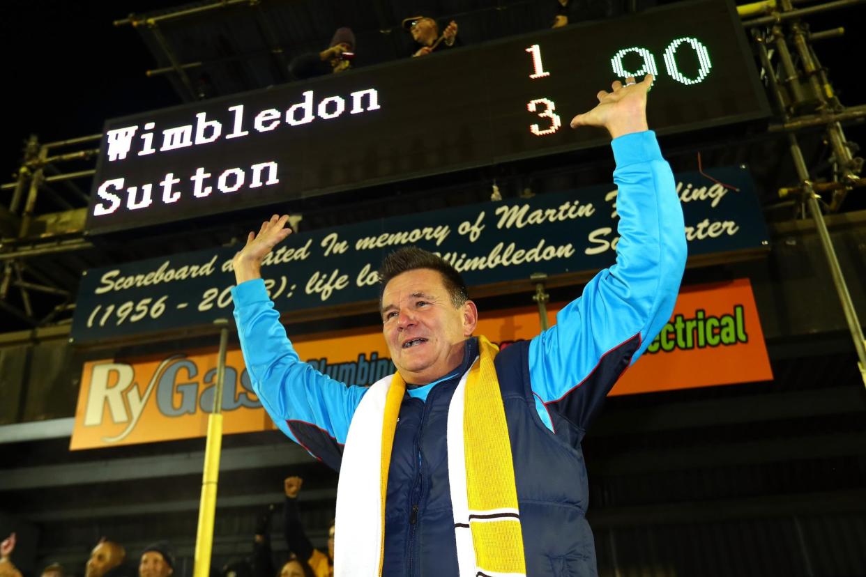 Elated | Sutton manager Doswell poses for pictures in front of the scoreboard at full time: Clive Rose/Getty Images