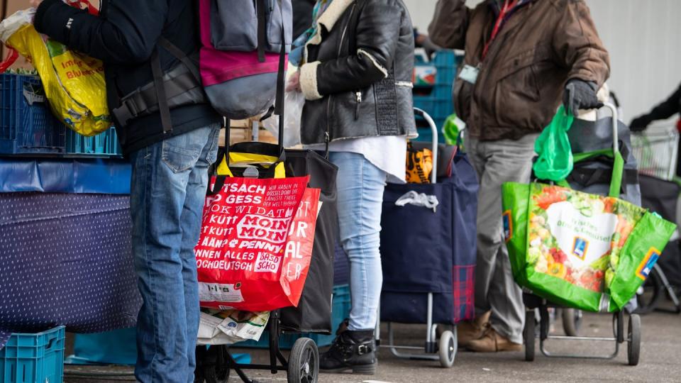 Gäste der Münchner Tafel stehen an der Ausgabestelle am Großmarkt.