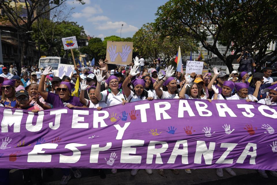 People carry a banner that reads in Spanish "Women and Work and Hope" during a march marking International Women's Day in Caracas, Venezuela, Friday, March 8, 2024. (AP Photo/Ariana Cubillos)