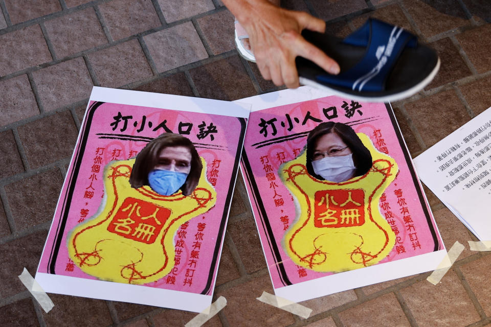 A pro-China supporter hits images of U.S. House of Representatives Speaker Nancy Pelosi and Taiwan President Tsai Ing-wen with a shoe, as she carries out the 