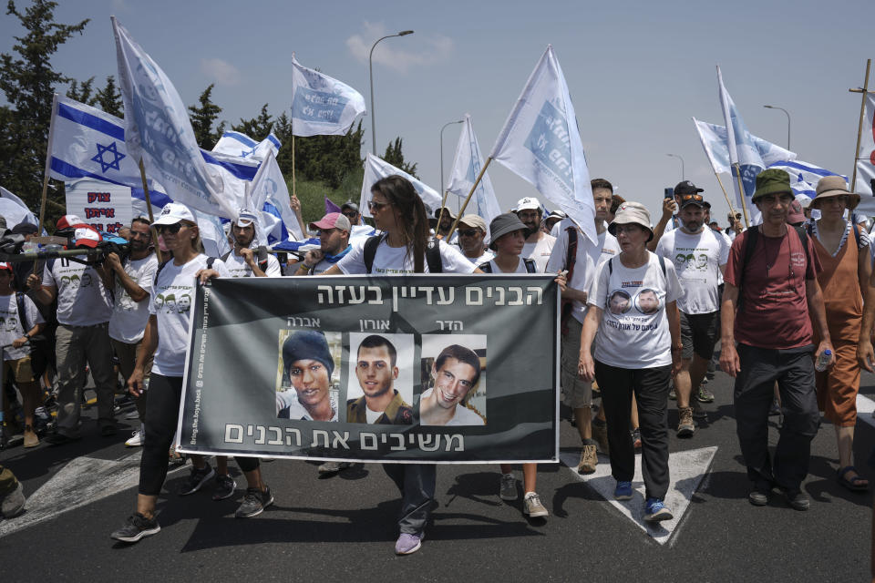 Supporters and family members of Israeli soldiers Hadar Goldin and Oron Shaul who were killed during the 2014 war in the Gaza Strip and captive Israeli civilian Avera Mengistu, march and calling for the return of their remains and the return of Mengistu and other Israelis held in Gaza back to Israel, near Kibbutz Yad Mordechai close to the Israeli Gaza border, Friday, Aug. 5, 2022. Hebrew on banner reads, "The boys are still in Gaza" and " bringing back the boys". (AP Photo/Ariel Schalit)