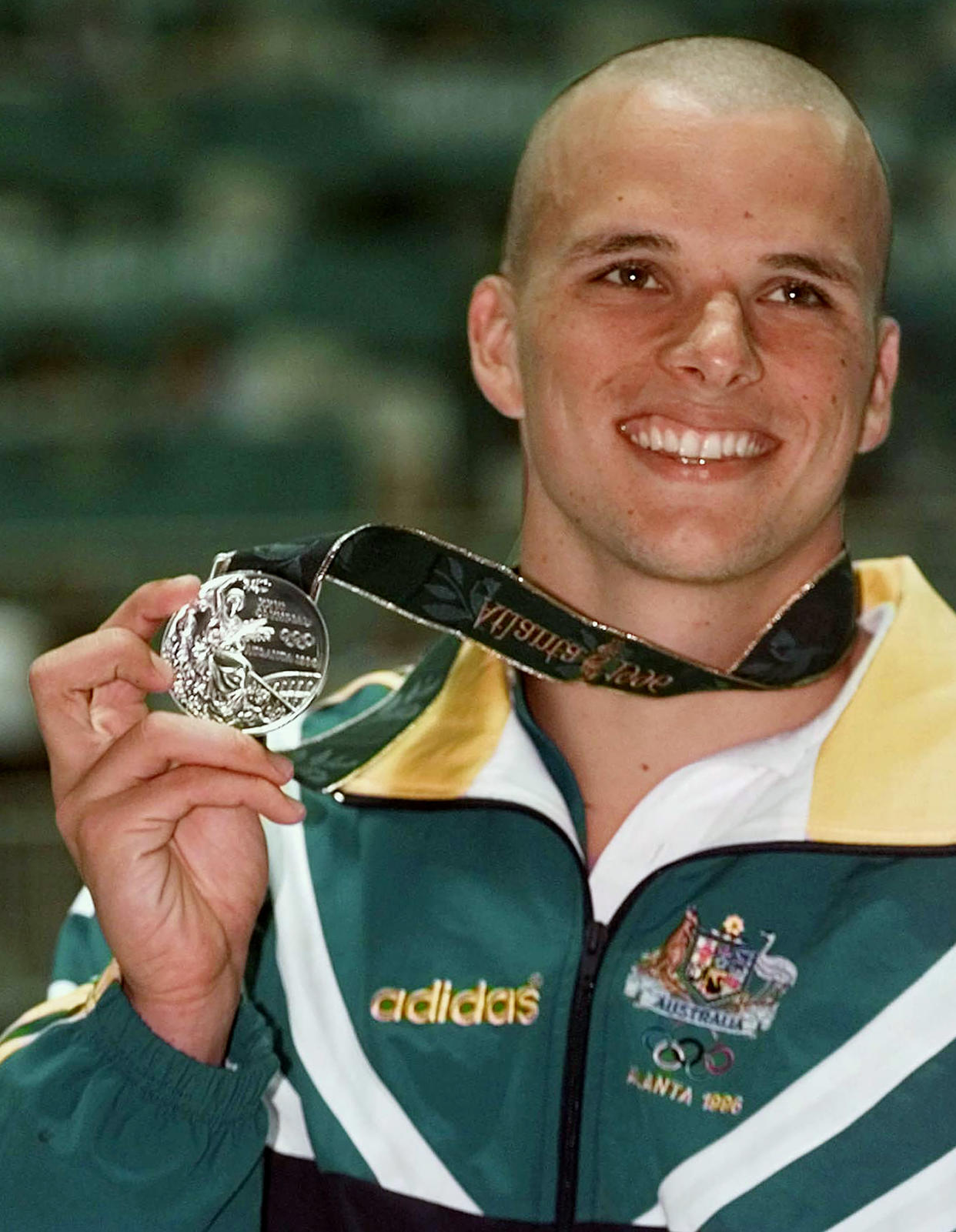 FILE - In this July 24, 1996, file photo, Scott Miller of Australia holds up his silver medal that he won in the men's 100 meter butterfly at the 1996 Summer Olympics in Atlanta. Miller was in custody on Tuesday, Feb. 16, 2021 charged with drug trafficking after Australian police seized methamphetamine valued at 2 million Australian dollars ($1.6 million) and accused him of directing a criminal syndicate. (AP Photo/Denis Paquin, File)