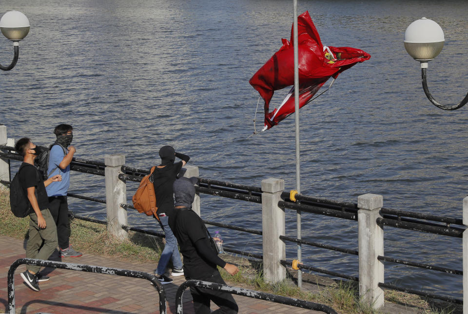 Protesters throw a Chinese national flag into the river after vandalizing it Sunday, Sept. 22, 2019, in Hong Kong. Hong Kong's pro-democracy protests, now in their fourth month, have often descended into violence. A hardcore group of the protesters says the extreme actions are needed to get the government's attention. (AP Photo/Kin Cheung)