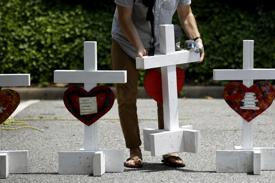 FILE - In this June 2, 2019, file photo, a volunteer prepares to place crosses for victims of a mass shooting at a municipal building in Virginia Beach, Va., at a nearby makeshift memorial. DeWayne Craddock, a city engineer who fatally shot 12 people in a Virginia Beach municipal building in 2019 “was motivated by perceived workplace grievances” that “he fixated on for years,” according to findings released by the FBI on Wednesday, June 9, 2021. (AP Photo/Patrick Semansky, File)