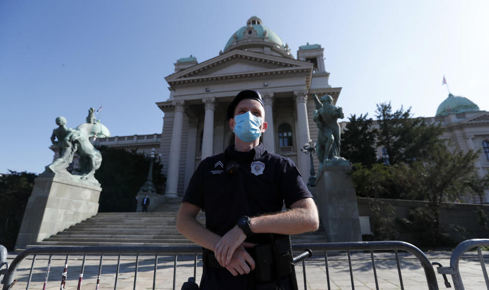 A Serbian police officer wearing a face mask to prevent the spread of coronavirus guards the parliament building before the inaugural parliament session in Belgrade, Serbia, Monday, Aug. 3, 2020. The Serbian parliament reconvened Monday amid protests by opposition and far-right supporters who claim the parliamentary election that was overwhelmingly won by the ruling populists was rigged. (AP Photo/Darko Vojinovic)