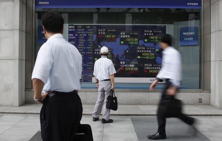 Pedestrians look at an electronic board showing the stock market indices of various countries outside a brokerage in Tokyo June 25, 2014. REUTERS/Yuya Shino