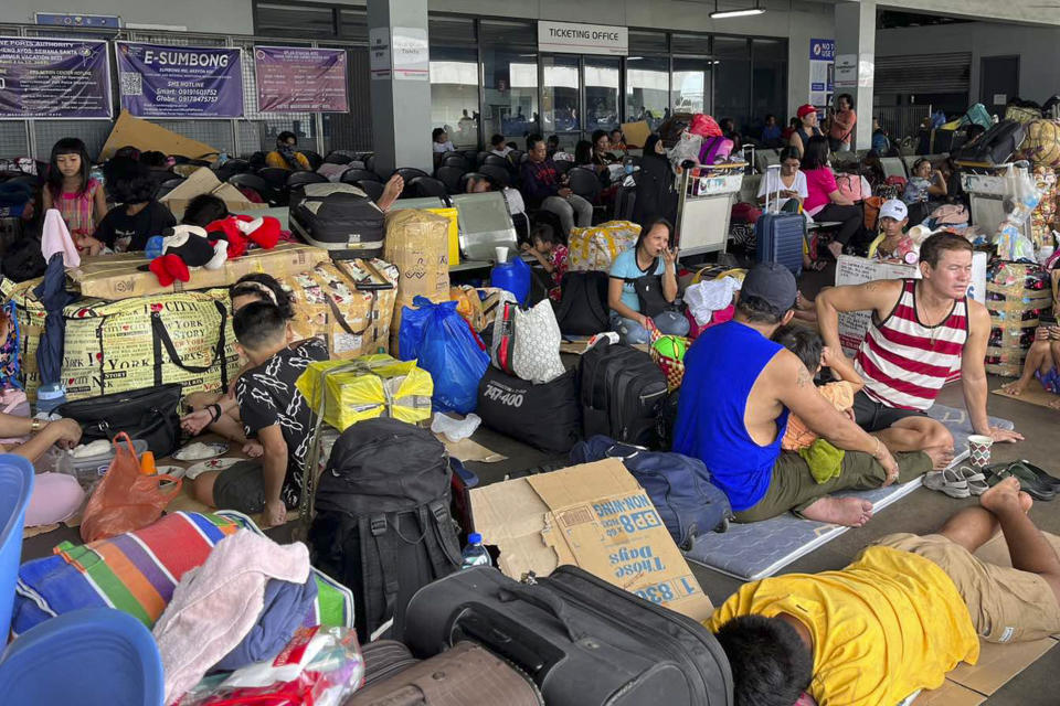 In this photo provided by the Philippine Coast Guard, stranded passengers stay at a passenger terminal after sea travel was suspended due to Typhoon Doksuri in Manila, Philippines on Tuesday July 25, 2023. The powerful typhoon blew closer to the northern Philippines on Tuesday, forcing thousands of evacuations and a halt to sea travel ahead of torrential rains and tidal surges up to 3 meters (nearly 10 feet). (Philippine Coast Guard via AP)