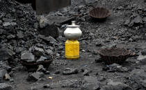 In this Oct. 23, 2019, photo, a metal vessel filled with drinking water stands at a coal loading site in the village of Godhar in Jharia, a remote corner of eastern Jharkhand state, India. The fires started in coal pits in eastern India in 1916. More than a century later, they are still spewing flames and clouds of poisonous fumes into the air, forcing residents to brave sizzling temperatures, deadly sinkholes and toxic gases. (AP Photo/Aijaz Rahi)