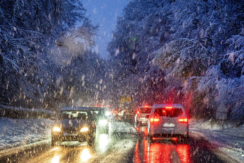 Commuters queue in heavy snowfalls on a country road in a forest of the Taunus region near Frankfurt, Germany, early Tuesday, Nov. 28, 2023. (AP Photo/Michael Probst)