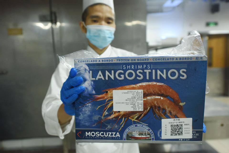 A cook shows a box of langosteens with a QR code for tracking purposes