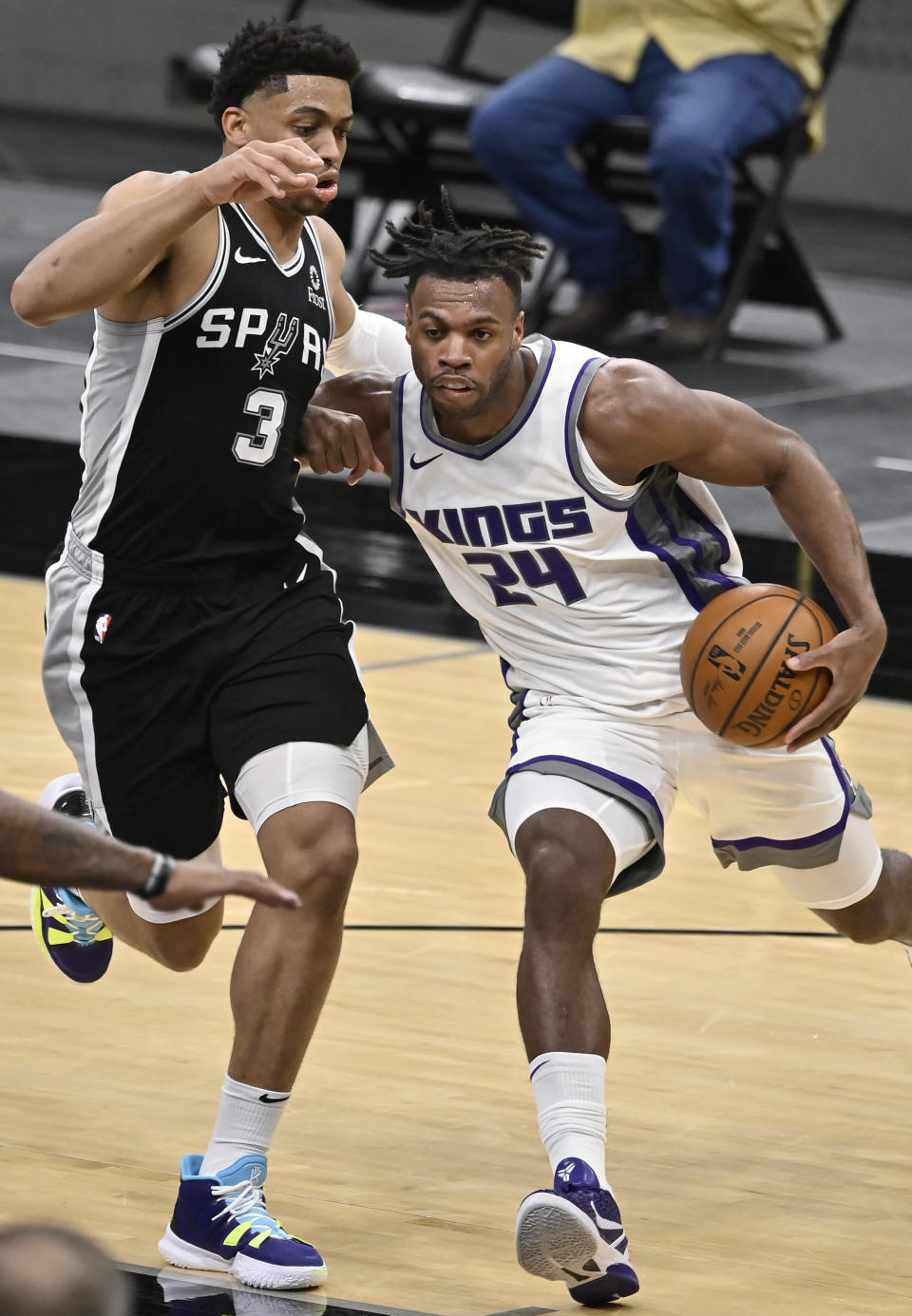 Sacramento Kings' Buddy Hield (24) drives against San Antonio Spurs' Keldon Johnson during the second half of an NBA basketball game Wednesday, March 31, 2021, in San Antonio. (AP Photo/Darren Abate)