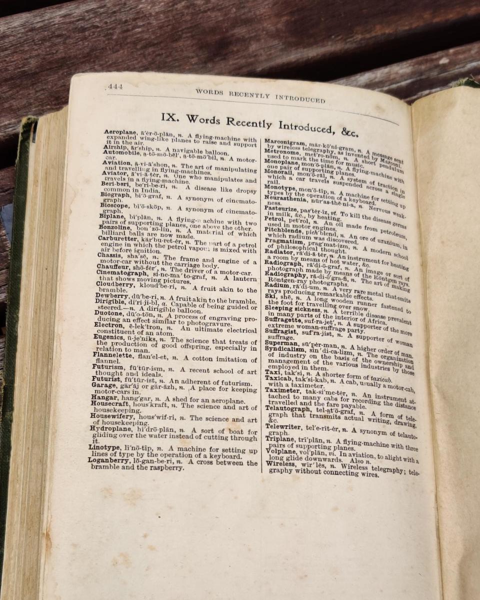 An old dictionary open to a page labeled "Words recently introduced," including Eugenics, Telewriter, Wireless, and Linotype