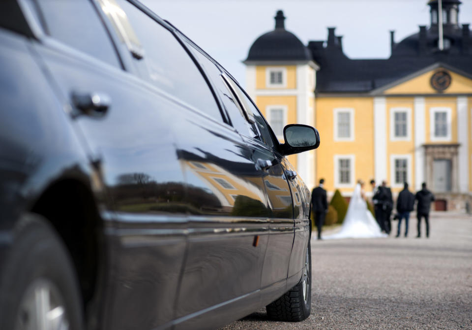 A limo with a wedding party in the background