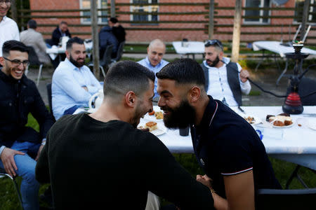 Guests from places within Denmark and Northern Europe sit together at the engagement party of a resident in Mjolnerparken, a housing estate that features on the Danish government's "Ghetto List", in Copenhagen, Denmark, May 6, 2018. REUTERS/Andrew Kelly