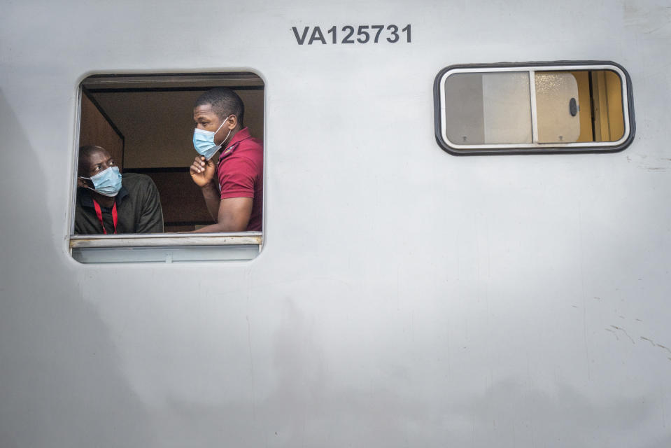 Train employes look out from the COVID-19 vaccination train parked at the Swartkops railroad yard outside Gqeberha, South Africa, Thursday Sept. 23, 2021. South Africa has sent a train carrying COVID-19 vaccines into one of its poorest provinces to get doses to areas where healthcare facilities are stretched. The vaccine train, named Transvaco, will go on a three-month tour through the Eastern Cape province and stop at seven stations for two weeks at a time to vaccinate people. (AP Photo/Jerome Delay)