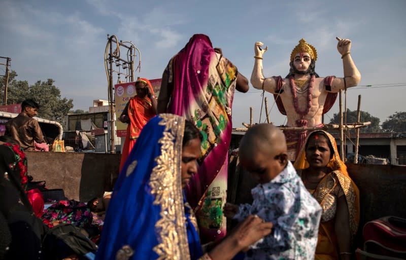 A statue of Hindu monkey god Hanuman is seen as devotees sit in a trailer attached to a tractor after offering prayers in a temple in Ayodhya