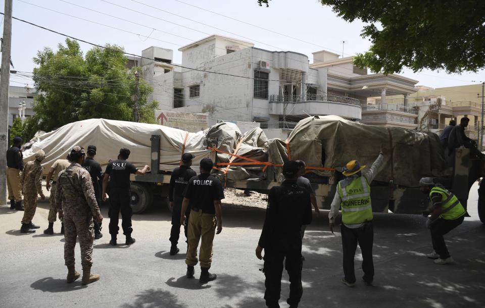 Pakistani security personnel stand guard near trucks carrying the wreckage of a Pakistan International Airlines plane from the crash site, Thursday, May 28, 2020 in Karachi, Pakistan. (AP Photo/Fareed Khan)