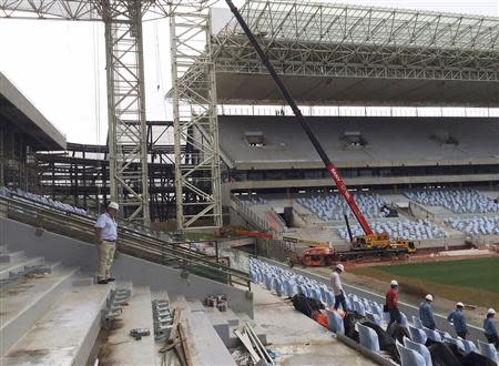 An official (L) from Brazil's World Cup organizers accompanies visitors on a tour inside the Arena Pantanal soccer stadium, which will host several matches of the 2014 World Cup in Cuiaba, February 13, 2014. REUTERS/Brian Winter