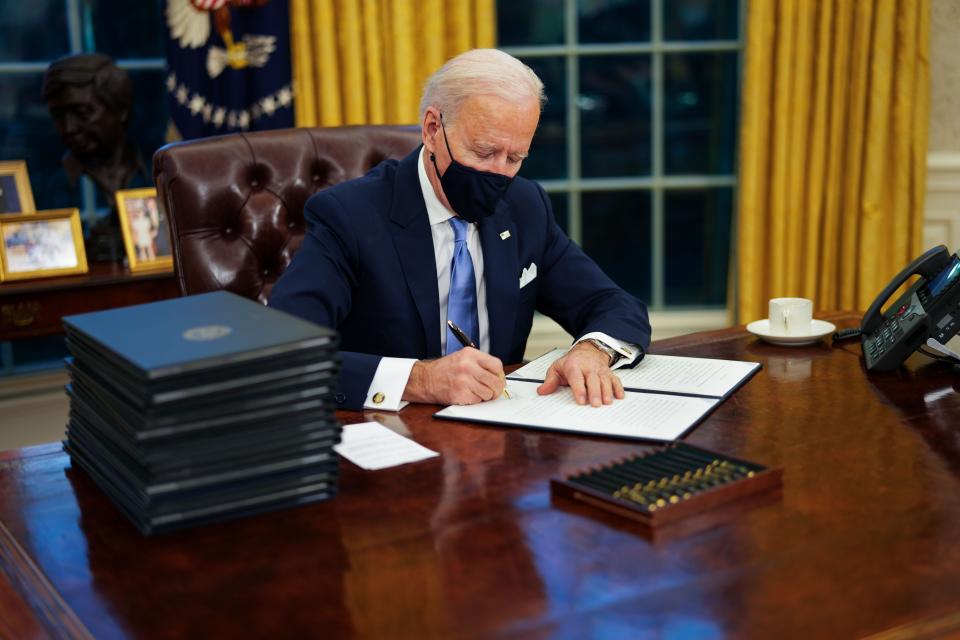 US President Joe Biden signs executive order on Covid-19 during his first minutes in the Oval Office (EPA-EFE)
