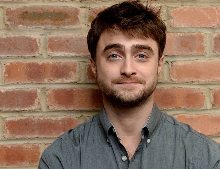 Daniel Radcliffe standing against a brick wall for a photograph