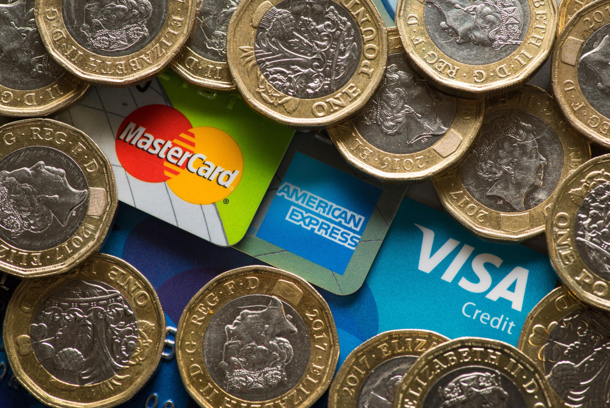 Mastercard, American Express and Visa credit cards with UK one pound coins.