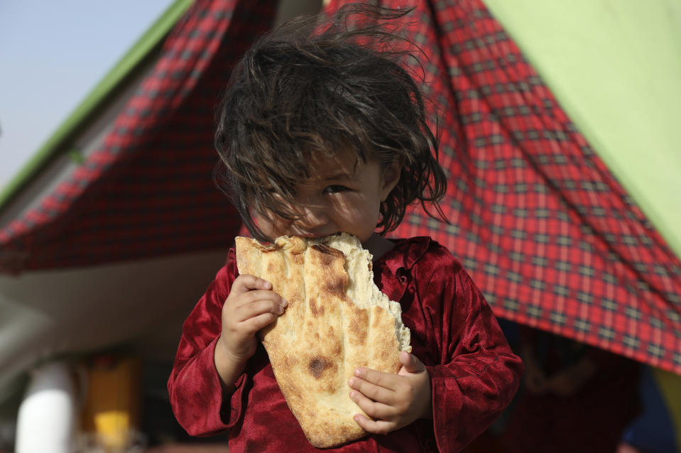 An internally displaced Afghan girl whose family fled their home due to fighting between the Taliban and Afghan security personnel, eats bread as she stand in front of her makeshift tent at a camp on the outskirts of Mazar-e-Sharif, northern Afghanistan, Thursday, July 8, 2021. As the Taliban surge through the north of Afghanistan, a traditional stronghold of U.S.-allied warlords and an area dominated by the country’s ethnic minorities, thousands of families like this girl’s are fleeing their homes, fearful of living under the insurgents’ rule. (AP Photo/Rahmat Gul)