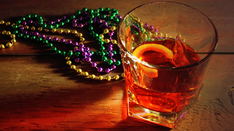 Sazerac cocktail with mardi gras beads on table