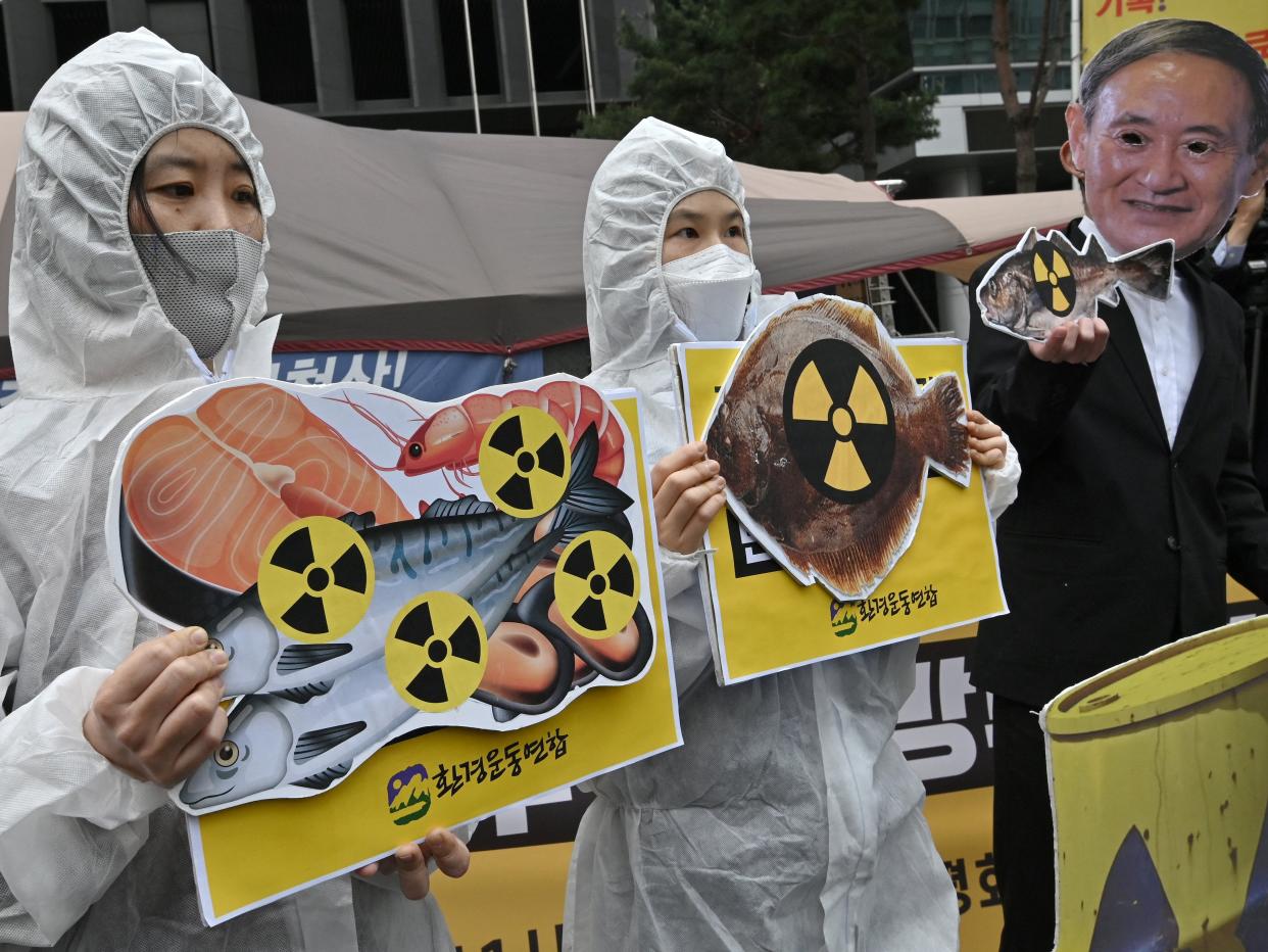 South Korean environmental activists protest outside the Japanese embassy at the decision, one wearing a mask of Japan’s prime minister Yoshihide Suga (AFP via Getty Images)