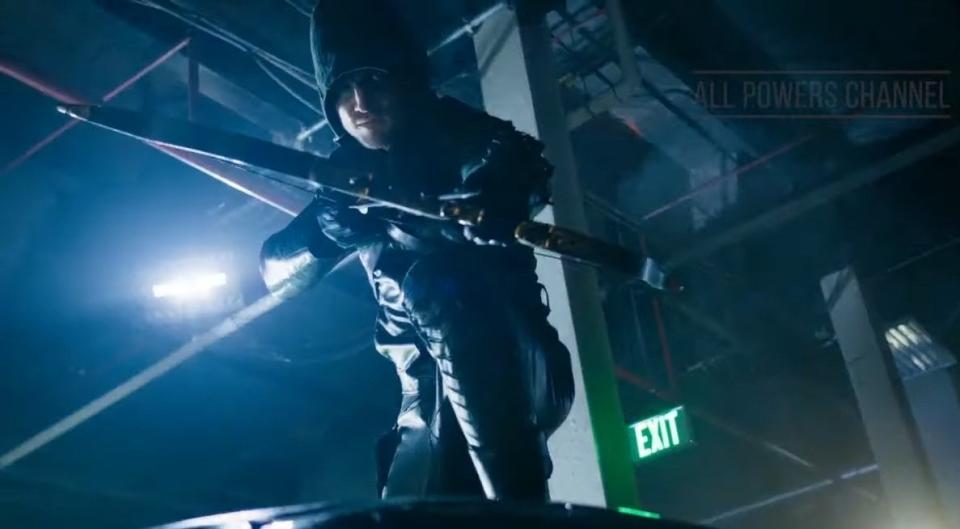 Green Arrow crouched on top of a car with his bow drawn in "Arrow"