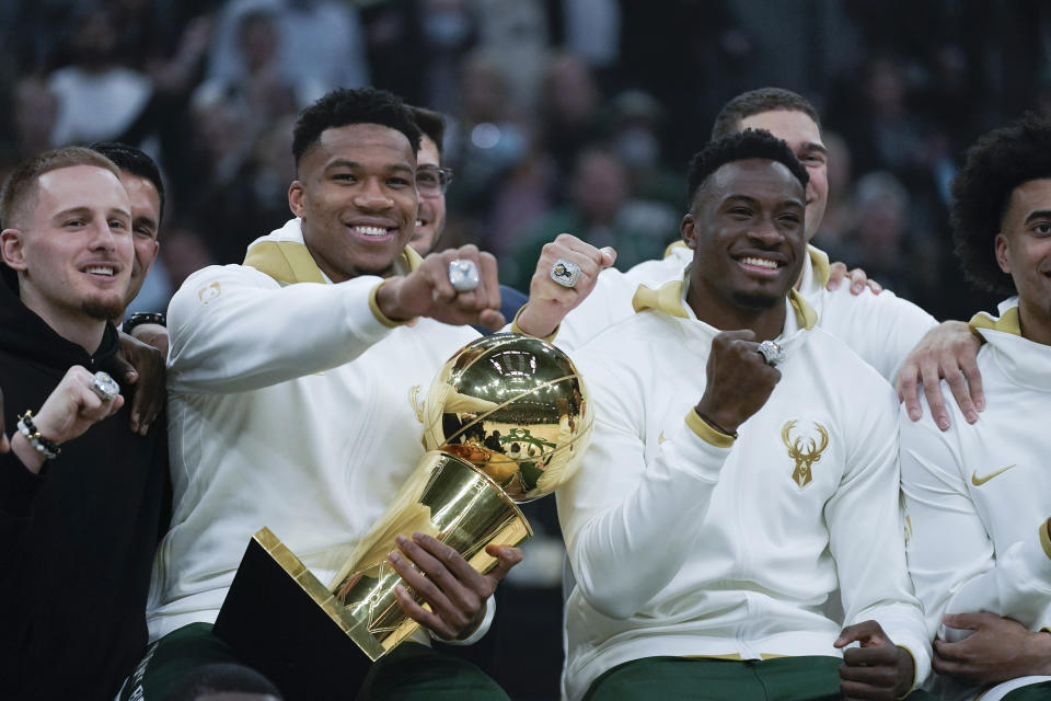 Milwaukee Bucks' Giannis Antetokounmpo, segundo de la izq, y Thanasis Antetokounmpo enseñando sus anillos en NBA (AP Photo/Morry Gash)